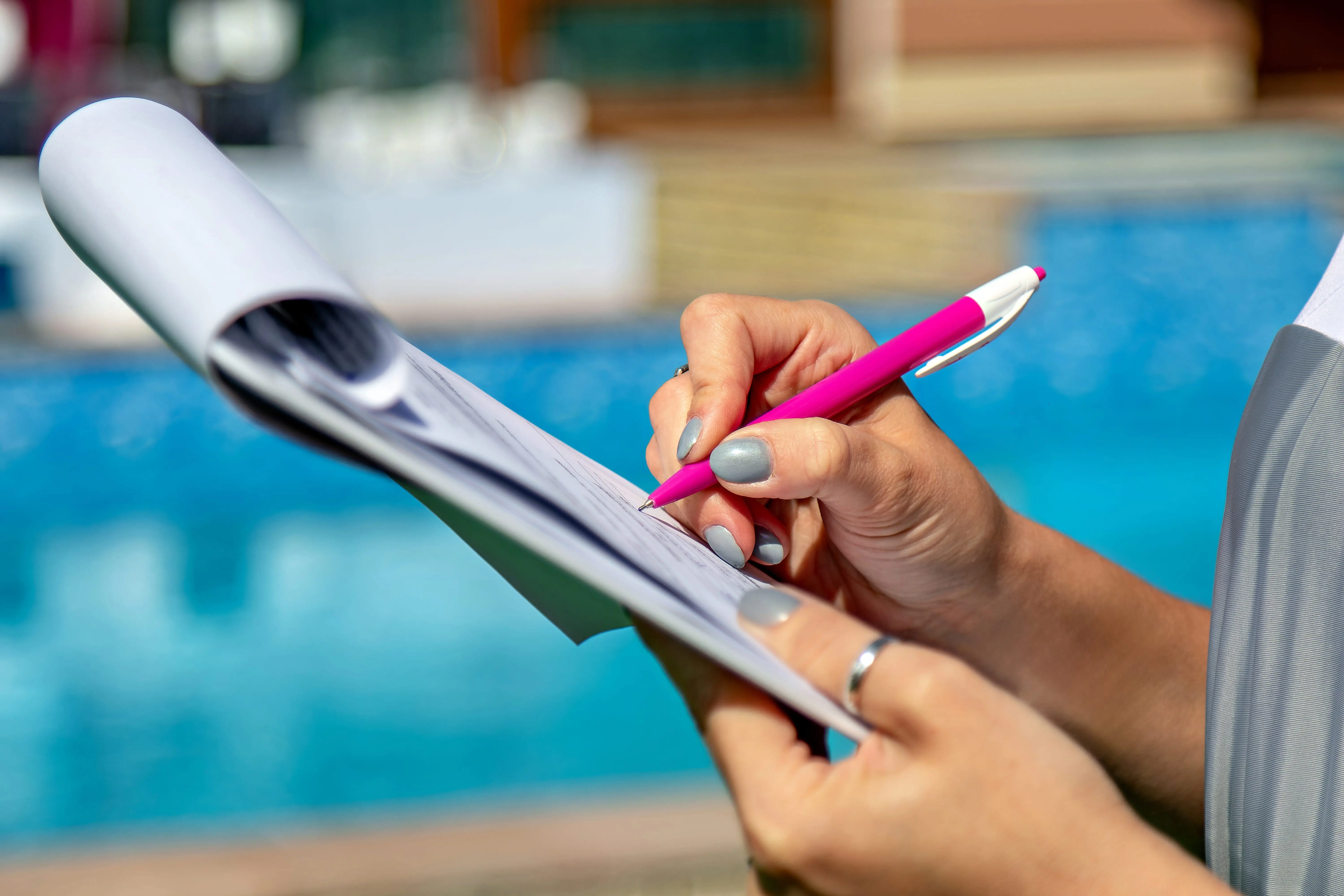 A person using a clipboard at the poolside